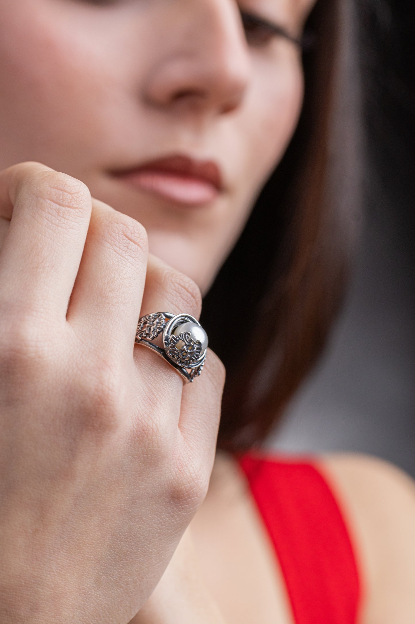Anello Aion in argento 925 con perla coltivata d'acqua dolce e maschere apotropaiche indossato al dito