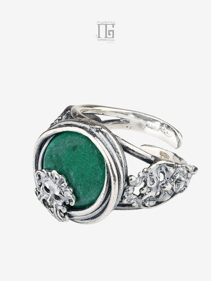 Vista sinistra dell'Anello Aion in argento 925 con pietra verde, filo intrecciato e tre maschere apotropaiche.