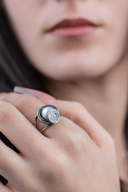 Anello artigianale in argento 925 con perla coltivata d'acqua dolce bianca e Disco di Festo della collezione Aion indossato al dito